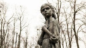 Holodomor memorial statue in Kyiv, Ukraine, depicting a solemn girl in autumn park.